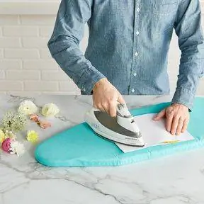 Использование утюга для отпаривания цветов на бирюзовой гладильной доске