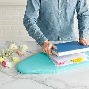 прижатие цветов книгой между листами бумаги на гладильной доске