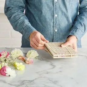 резинки постучали по квадратам плитки, чтобы прижать цветы