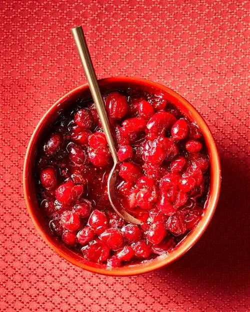 клюквенный соус в красной миске с латунной ложкой клюквенный соус в красной миске с латунной ложкой