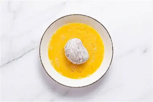 обмакивание посыпанного мукой мяса и яиц в яичную смесь для приготовления яиц по-шотландски