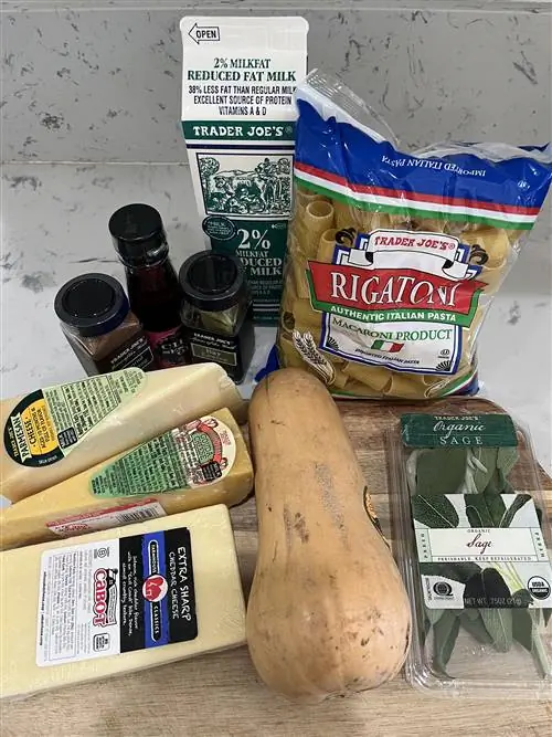 Ингредиенты для макарон с мускатной тыквой и сыром, включая макароны, молоко, мускатную тыкву, сыр и травы.