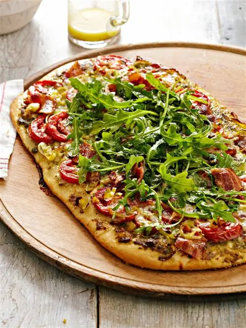 Пицца с песто, беконом и помидорами с верхушкой для салата из рукколы