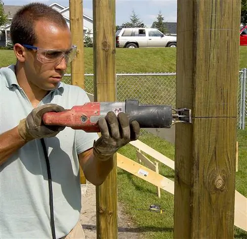 мужчина режет столб сабельной пилой