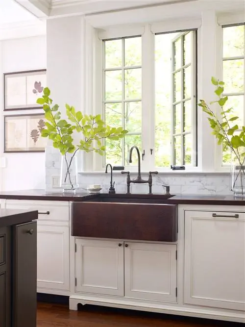 вертикальный снимок белой кухни с медной раковиной у окна