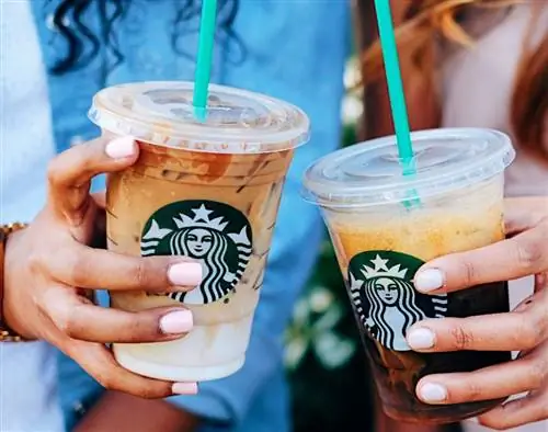 Две руки держат кофе со льдом из Starbucks
