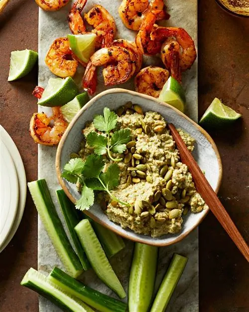 Дип из тыквенных семечек в миске с креветками и дольками лайма сбоку