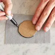 используя трафарет, чтобы обвести круг, чтобы вырезать ткань для пучка пуговиц