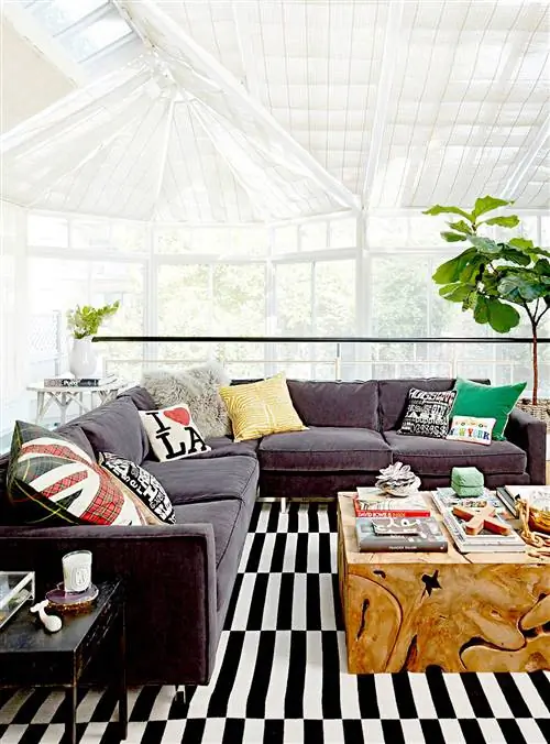 Крыльцо с полосатым ковриком, двумя диванами и деревянным столом.