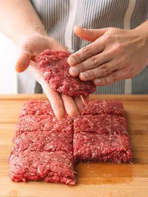сырой говяжий фарш, разделенный на кусочки, формирующий котлеты