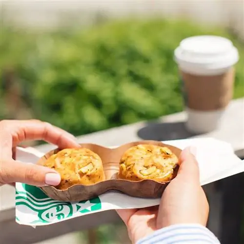 Женские руки держат упаковку из двух яичных укусов Starbucks Chicken Chorizo Sous Vide