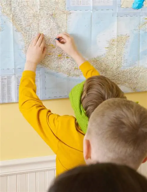 ребенок играет в тестовую игру по географии с завязанными глазами