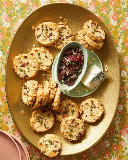 Овсяное печенье с голубым сыром и сушеной вишней на золотой тарелке с голубым сыром и сушеной вишней сбоку