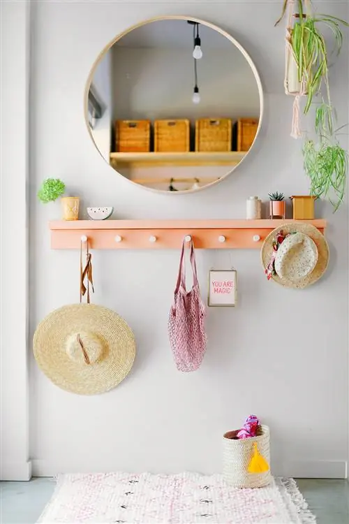 коралловая подвесная полка и круглое зеркало в прихожей