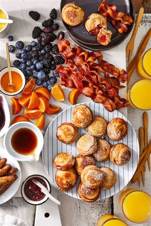 поздний завтрак с пахтой Ebleskivers (датские блины), беконом, фруктами и чашками сиропа и джема