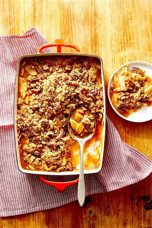 Запеченный орехово-карамельный яблочный чипс в красной сковороде с большой ложкой