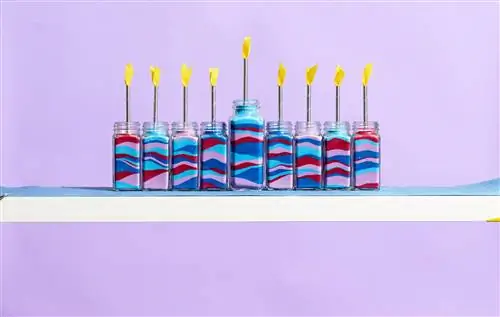 ханукальные меноры ручной работы в разноцветных банках на полке на фиолетовом фоне