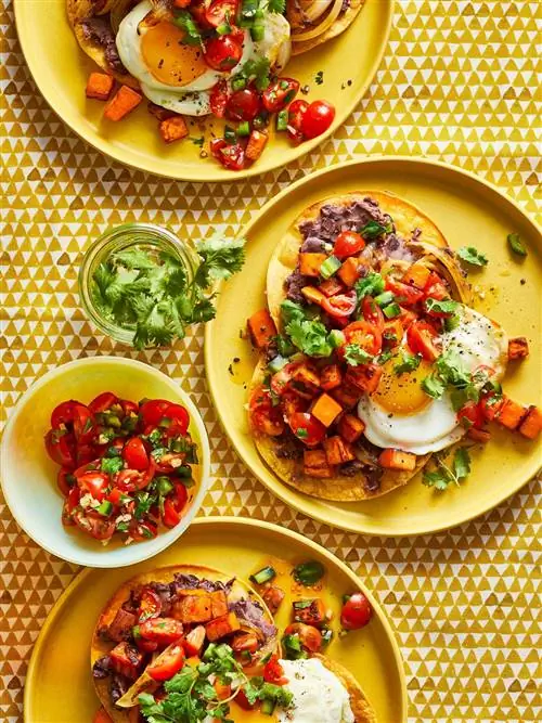 Сладкий картофель-черная фасоль Huevos Rancheros с жареным яйцом на желтой тарелке
