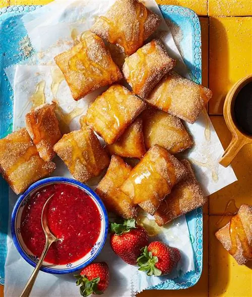 Sopaipillas на пергаментной бумаге, сбрызнутой медом Sopaipillas на пергаментной бумаге, сбрызнутой медом