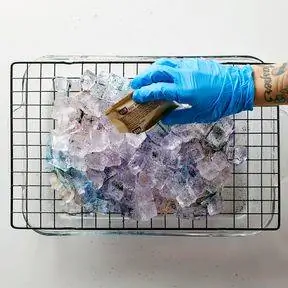 рука в перчатке льет краску на лед