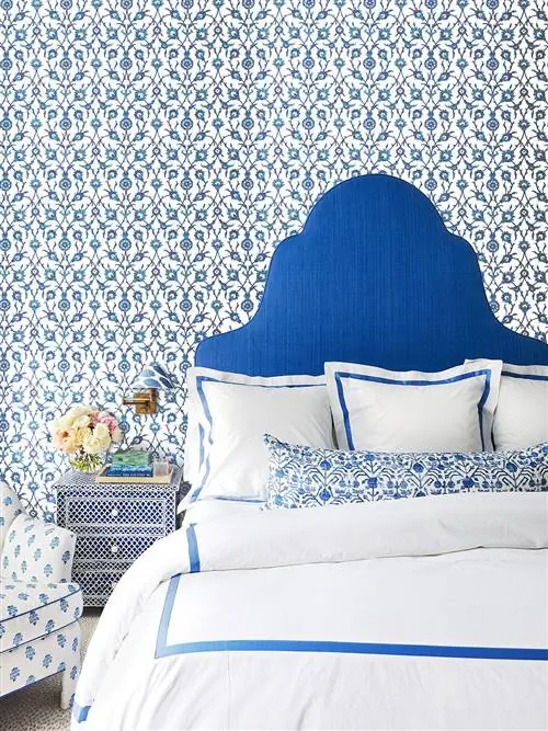 снимок спальни с голубыми узорчатыми обоями и изголовьем кровати