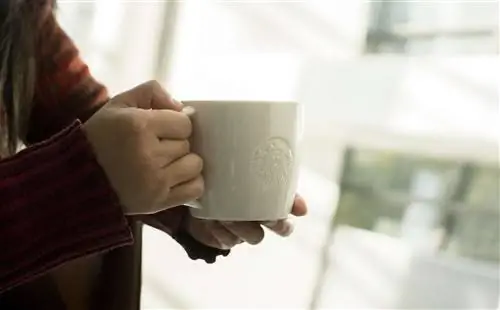 Женщина в красном свитере с белой кружкой Starbucks