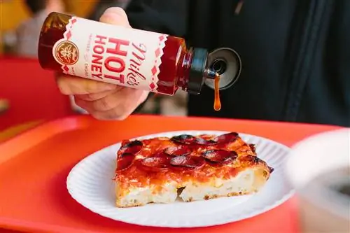 Бутылка горячего меда Майка поливают пиццу