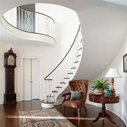 изогнутая белая традиционная лестница с темной мебелью