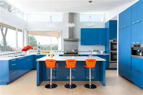 Оранжевые табуретки у острова в современной синей кухне