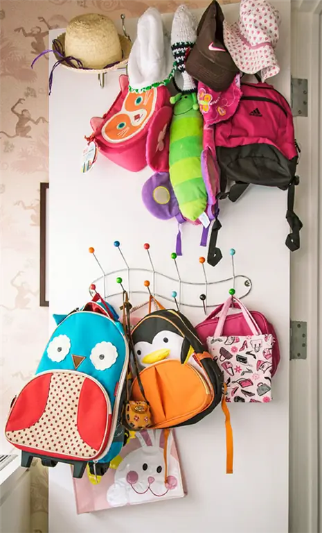 красочные детские рюкзаки и шапки висят на двери