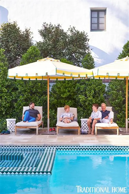 семья сидит в креслах у бассейна в испанском колониальном доме