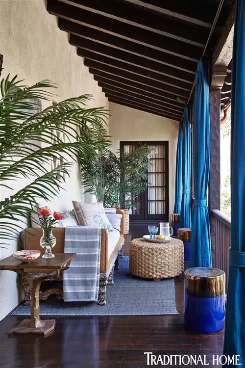 испанское колониальное крыльцо с королевскими синими занавесками и пальмовыми растениями