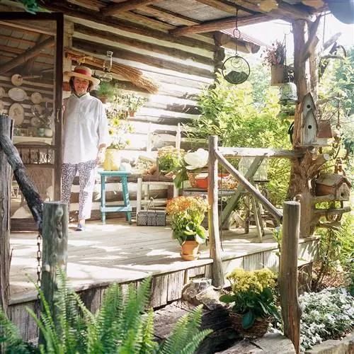 садовник стоит на крыльце с растениями