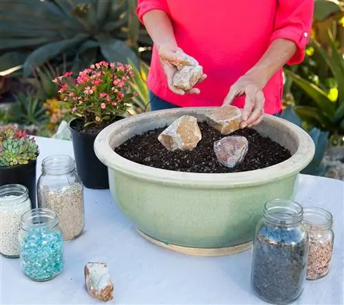 женщина кладет камни на почву в контейнере в саду