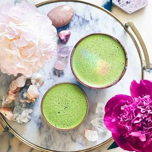 розовый кварц, аметист и селенит на круглом столе с розовыми пионами и зелеными напитками