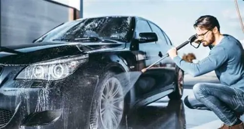 Мужчина моет машину мойкой высокого давления с автомобильным мылом