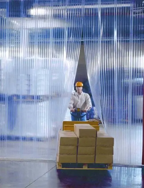 рабочий проходит через занавески из ПВХ