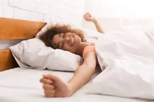 Счастливая женщина просыпается после сна на кровати