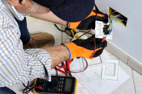 iStock-894986152 рабочие перчатки электрик, работающий на розетке