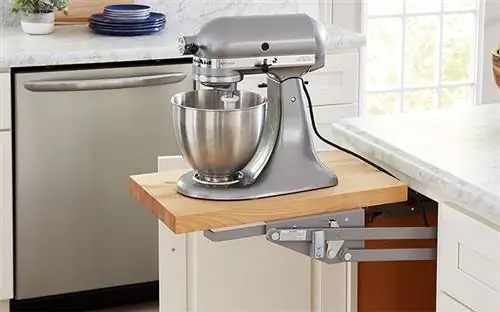 Крупный план красивого серебряного стационарного миксера, стоящего на выдвижной полке из индивидуального шкафа.