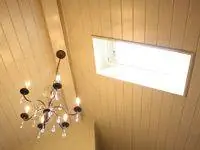 Сводчатый потолок ванной комнаты с потолочным окном и люстрой.
