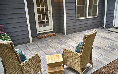 Брусчатка Pavestone Avant Linear во внутреннем дворике, вид из-за двух шезлонгов, обращенных к заднему входу в дом.