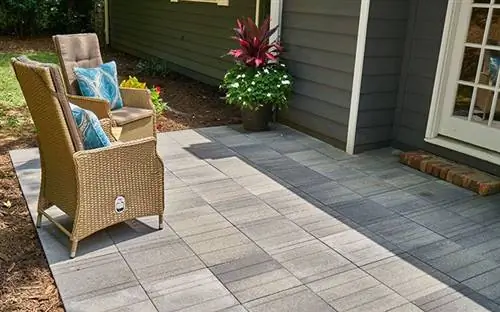 Вид сбоку на брусчатку Pavestone Avant Linear в сером патио в солнечный день.