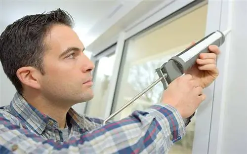 Мужчина затыкает окна, чтобы утеплить свой дом