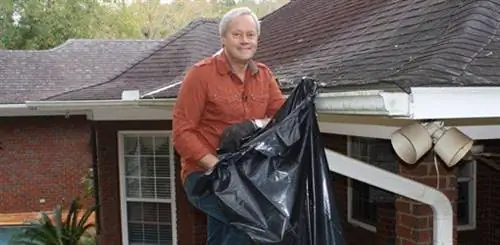 Стоя на лестнице, чистя желоба.