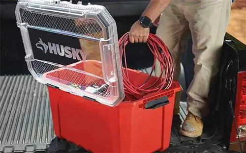 Мужчина кладет удлинитель в профессиональную сумку для хранения Husky с прозрачной пластиковой крышкой.