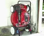 Газонокосилка Toro SmartStow хранится у стены в гараже.