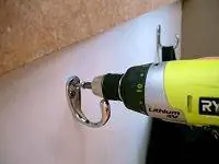 Аккумуляторный шуруповерт Ryobi закручивает шуруп в стену Аккумуляторный шуруповерт Ryobi закручивает шуруп в стену