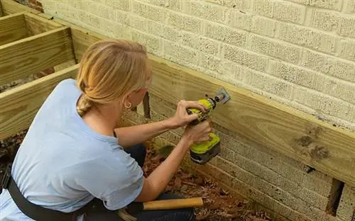 Челси Липфорд Вульф прикручивает бухгалтерскую доску к дому.