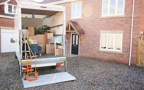 Движущийся грузовик с открытой задней дверью, обнажающей тяжелые предметы спереди и коробки сзади.